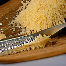 the parmesan cheese is shredded using a grater.