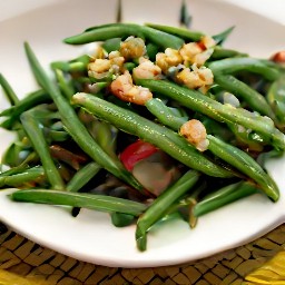 a green bean salad that has been mixed with vinaigrette and chopped walnuts.