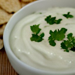a bowl of tahini sauce with parsley on top.