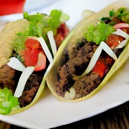 a serving plate with the beyond meat mixture, guacamole, diced tomatoes, shredded lettuce and remaining chopped cilantro.