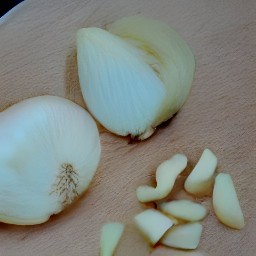 a peeled onion that has been cut in half lengthwise and then sliced into wedges.