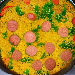 a paella dish with onions, tomatoes, bell peppers, garlic, and paella rice.