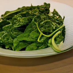 the wilted spinach is transferred to a third plate.