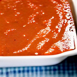 a baking dish with olive oil and spaghetti sauce in it.