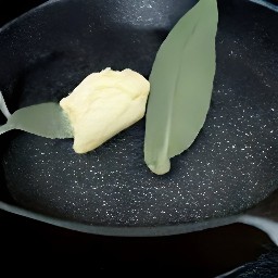 a skillet with plant-based butter and sage leaves.