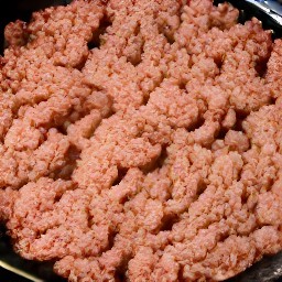 the meatless burgers patties are crumbled with a wooden spoon.