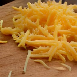 the vegan cheddar cheese is shredded with a grater.