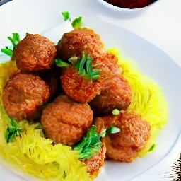 the spaghetti has been transferred to a serving plate and is topped with cooked meatballs with tomato sauce.