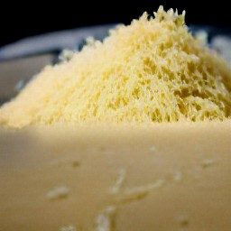 the parmesan cheese is shredded into small pieces using a grater.
