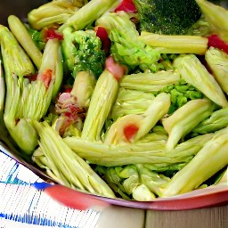 a dish of pasta with grilled vegetarian bacon, broccoli, and pesto, topped with grated parmesan cheese.