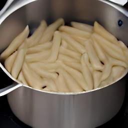 a pot of boiling water with salt and penne pasta added.