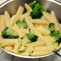 the pasta, broccoli, and snow peas are drained in a colander.