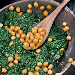 a dish of cooked chickpeas with spinach, red bell peppers, and ginger.