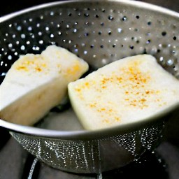 the halloumi cheese is rinsed and drained in a colander.