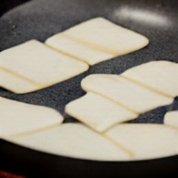 the halloumi cheese slices are placed in a non-stick frying pan and cooked for one minute.