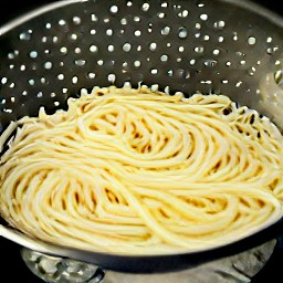 the cooked spaghetti is drained in a colander.