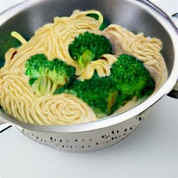 cooked spaghetti and broccoli that have been drained in a colander.