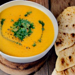 a curried squash with lentil and coconut soup with a side of naan bread.