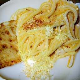 a plate of linguine pasta with butter, chili flakes, black pepper, and parmesan cheese mixed in, as well as fried bread on the side.