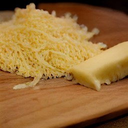 the parmesan cheese is shredded into small pieces using a grater.