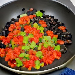 a dish of stir-fried tomatoes, garlic, onions, green chili peppers, red chili peppers, dried oregano, and ground cumin with black beans.