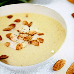 a bowl of creamy soup with some spicy mixed nuts scattered on top.