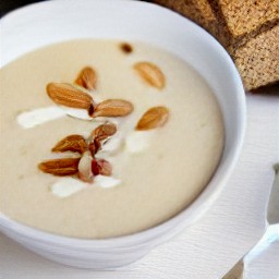 a veggie blended soup with almonds served with rye bread.