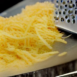 the parmesan cheese is shredded using a grater.