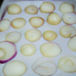 onion slices in a baking tray with olive oil over them.