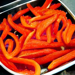 the red bell pepper strips are transferred to a roasting tin.