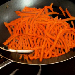 a stir-fry with sesame oil, carrot batons, chopped red bell peppers, ginger, and garlic.