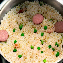 a pot of rice with peas and vegetarian sausage.